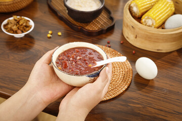 Traditional Red Bean Porridge in Hands with Asian Kitchen Setting and Steamer Basket