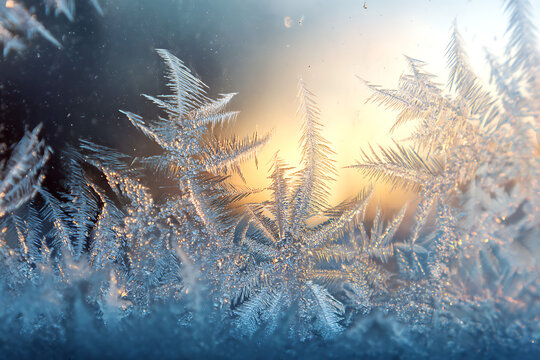 Gorgeous winter frost patterns forming delicate icy crystals on a window pane at sunrise