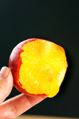 Fresh Yellow Nectarine with Red Skin Held in Hand Showing Juicy Flesh