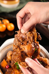 Hand Holding Tender Braised Oxtail Meat with Rich Sauce - Slow Cooked Comfort Food