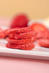 Freeze-Dried Strawberry Slices Stacked on Plate with Fresh Berries in Background - Healthy Snacking Concept