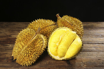 Fresh Durian Fruit with Golden Spiky Shell and Creamy Yellow Pulp on Wooden Table