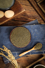 Raw millet grains in bowl with wooden spoon on rustic kitchen table - healthy cereal ingredient