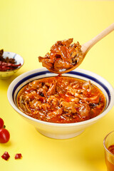 Spicy Marinated Squid in Red Sauce with Wooden Spoon on Yellow Background