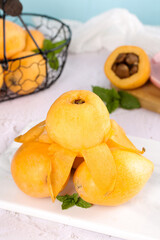 Fresh Loquat Fruits with Seeds and Mint Leaves on White Marble Surface