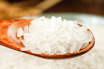 White rice grains on wooden spoon closeup studio photography