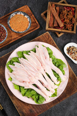 Raw Duck Feet with Fresh Lettuce and Aromatic Spices on Wooden Cutting Board