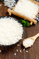 Premium white rice grains in wooden bowl and spoon display on rustic wooden background for healthy cooking ingredients