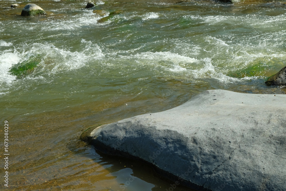 Poster view of large rocks on the edge of a clear mountain river. for advertising product placement design 