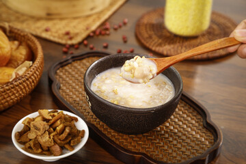Traditional corn oatmeal porridge breakfast with nuts and wooden spoon in rustic kitchen setting