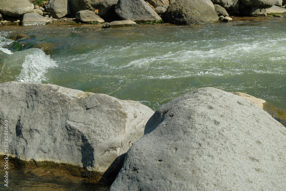 Poster view of large rocks on the edge of a clear mountain river. for advertising product placement design 