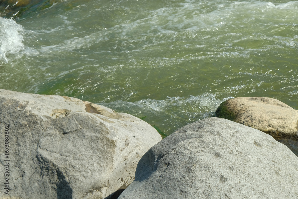Poster view of large rocks on the edge of a clear mountain river. for advertising product placement design 