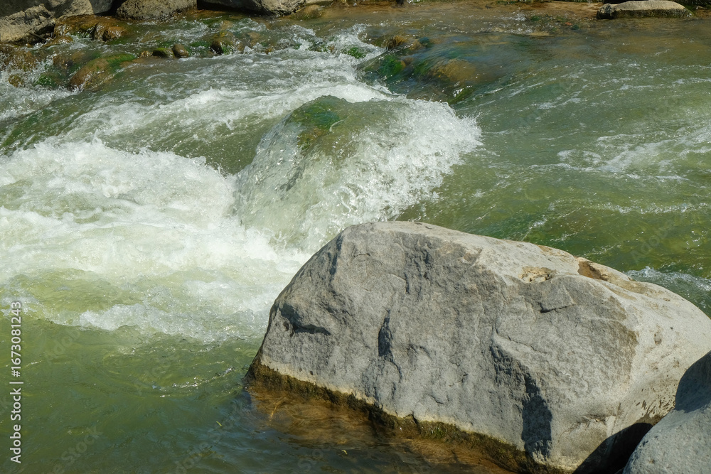 Poster view of large rocks on the edge of a clear mountain river. for advertising product placement design 