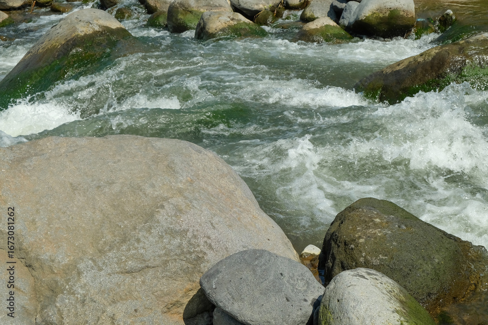 Poster view of large rocks on the edge of a clear mountain river. for advertising product placement design 