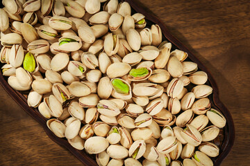 Fresh Pistachios with Green Kernels in Wooden Bowl on Rustic Wood Table