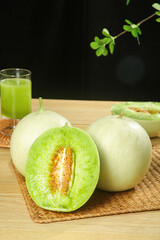 Fresh Jade Green Honeydew Melons with Cream Skin and Green Juice on Wooden Board