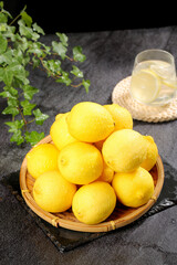 Fresh Yellow Lemons in Bamboo Basket with Lemon Water and Mint on Dark Slate Background