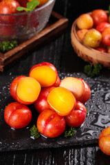 Fresh Red Plums with Golden Flesh on Dark Slate Surface