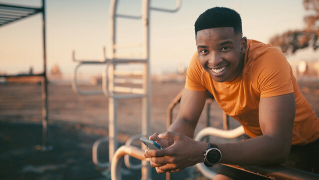Portrait, athlete and man with smartphone, outdoor gym and smile for fitness, exercise or training. Happy, black person and research workout tips on mobile app, healthy and wellness in Nigeria