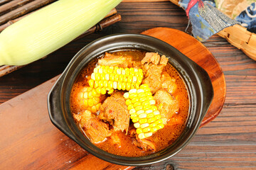 Hearty Corn and Rib Soup in Clay Pot on Wooden Table - Traditional Comfort Food