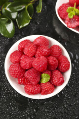 Fresh Red Raspberries in White Bowl with Mint Leaves on Dark Surface