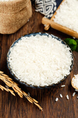 White rice in decorative bowl with wheat stalks on rustic wooden table - healthy grain food...