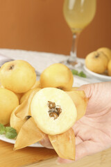 Fresh Loquat Fruits Display with Hand Holding Sliced Fruit on White Plate Light Background