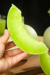 Fresh Green Jade Melon Slice from Shandong China Held in Hand Showing Juicy Flesh and Natural...