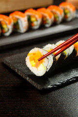 Fresh Sushi Rolls with Chopsticks on Black Slate Platter - Japanese Cuisine