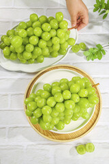 Fresh Green Grapes in Bowls on White Wooden Table with Hand Reaching for Healthy Fruit