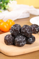 Dried Xinjiang Tianshan Plums Sweet and Sour Chinese Preserved Fruit on Wooden Board