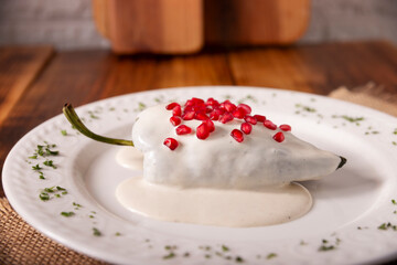 Chiles en Nogada, a typical Mexican dish. Poblano chile stuffed with meat and fruit, topped with a...