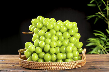 Fresh Green Grapes in Wicker Basket on Wooden Table with Natural Plant Background