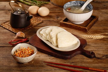 Traditional Asian dumplings on wooden base with soup and chopsticks kitchen table setting