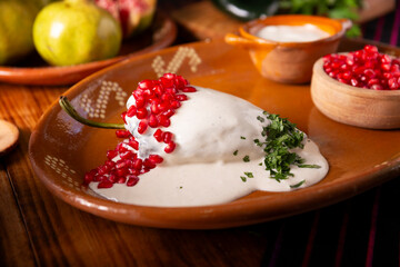 Chiles en Nogada, a typical Mexican dish. Poblano chile stuffed with meat and fruit, topped with a...
