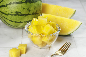 Yellow Watermelon Slices and Cubes in Glass Bowl - Fresh Summer Fruit on White Wood Background