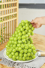 Fresh Green Grapes Being Picked by Hand on Wooden Table in Sunshine