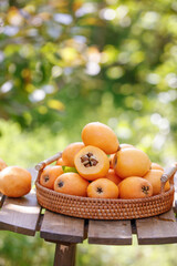 Fresh Loquat Fruits in Wicker Basket Display on Wooden Table with Natural Garden Background