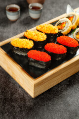 Japanese Sushi Platter with Colorful Roe and Seaweed Rolls on Wooden Board