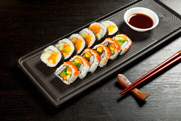 Fresh Sushi Rolls with Seaweed and Rice on Black Platter with Soy Sauce and Chopsticks