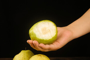 Fresh White Guava Fruit with Creamy Soft Heart-Shaped Center in Hand on Black Background