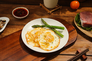 Delicious omelette with asparagus on plate - healthy breakfast meal on wooden table