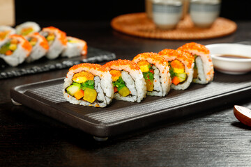 Delicate Sushi Rolls with Seaweed Wrapped Rice and Fresh Vegetables on Black Wooden Platter