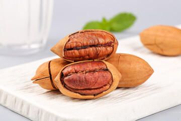 Obraz premium Fresh Pecan Nuts in Shells on White Wooden Board - Healthy Snack Food Studio Photography