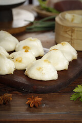 Steamed meat buns on wooden background with bamboo steamer - traditional Asian dumplings