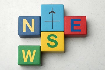 Wooden Blocks Arranged in a Cross Shape Spelling NSEW with Compass Arrow direction north