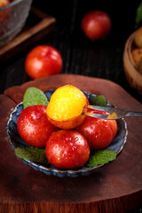 Fresh Red Plums from Guangdong Province China in Bowl with Mint Leaves on Wooden Table