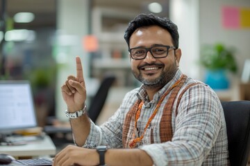 Happy Indian man working in the office, sitting at the desk, holding a mobile phone and enjoying success showing a victory gesture with his hand, Generative AI