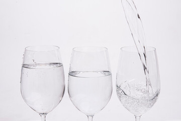 Three glasses of wine with water poured into them in the concept of quitting alcohol.