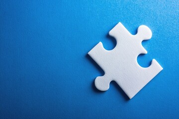 Obraz premium Single white puzzle piece on vibrant blue background